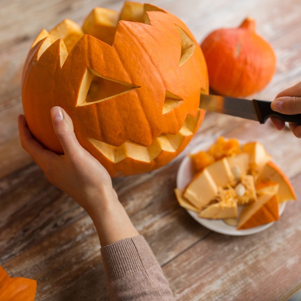 Person with knife cutting a pumpkin for Halloween