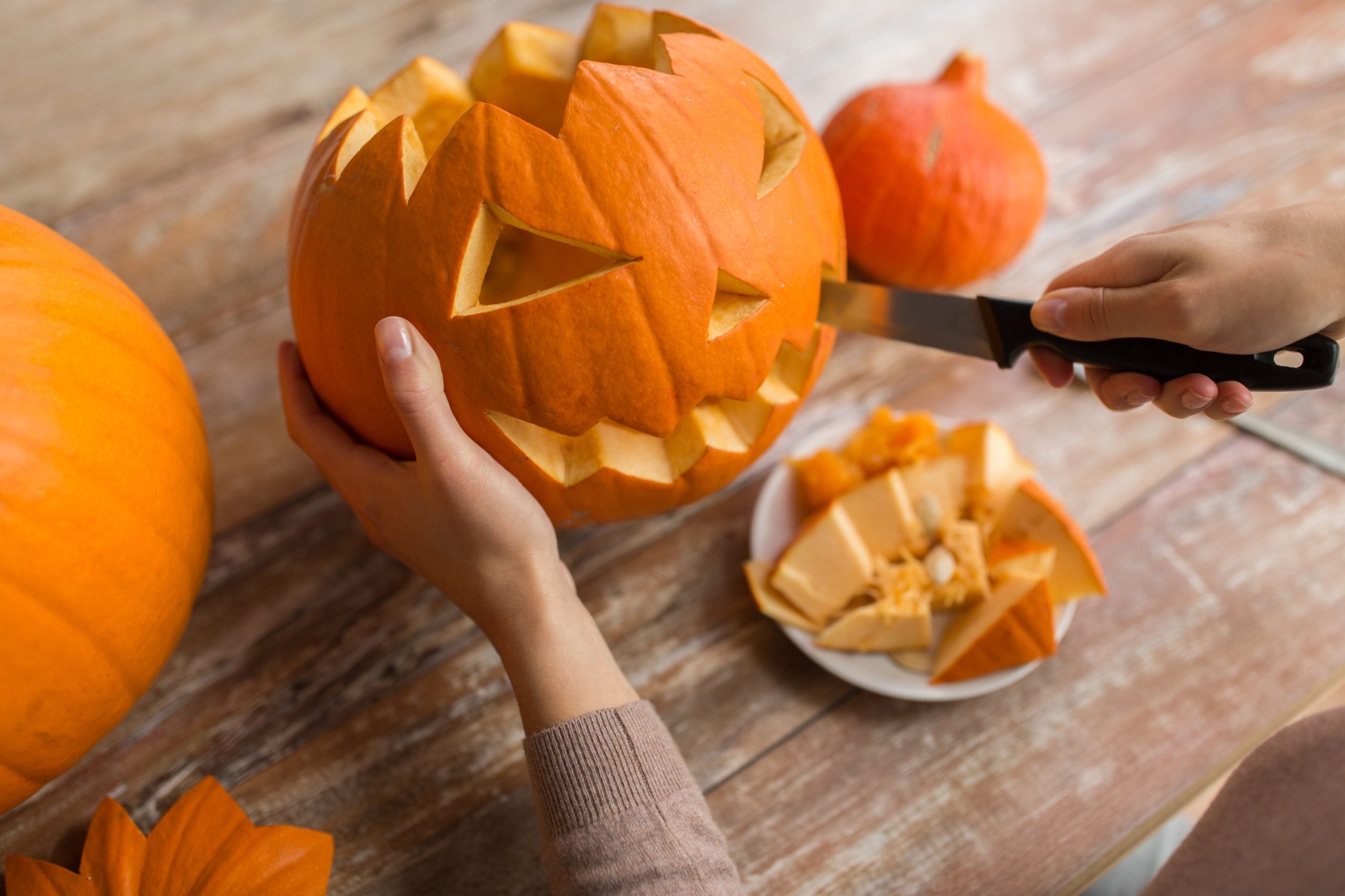 person with knife cutting a pumpkin for halloween