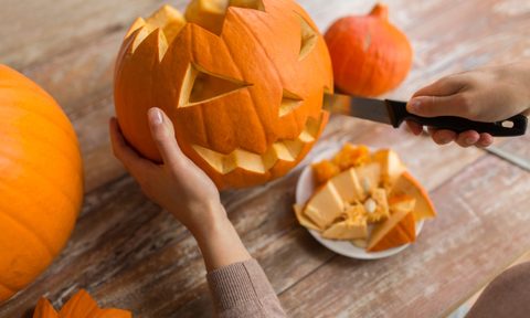 Person with knife cutting a pumpkin for Halloween