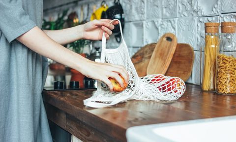 Woman taking fruit out of a cloth bag on table