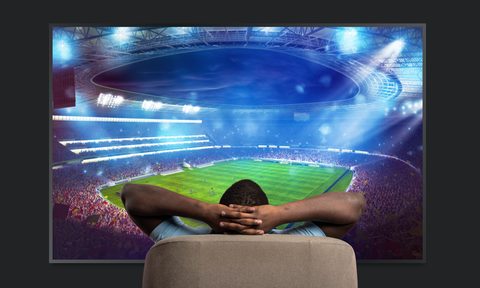 Man in recliner watching big screen TV in his man cave.