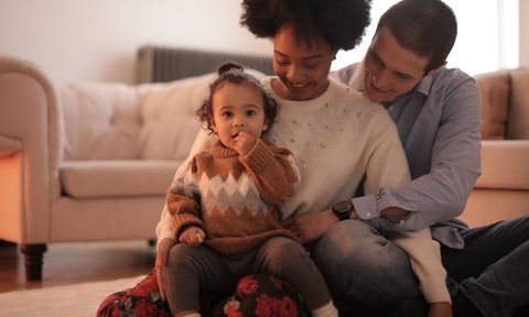 Family sitting on the floor near white couch
