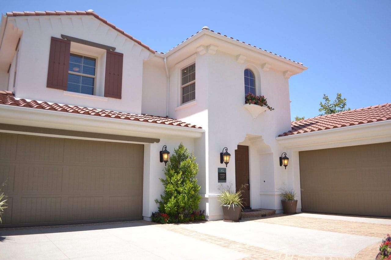 Two perpendicular garage doors on white two-story home