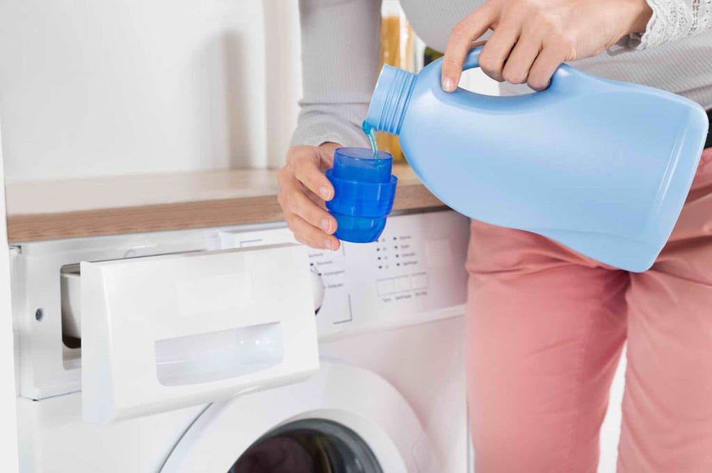 Person pouring laundry detergent into cup
