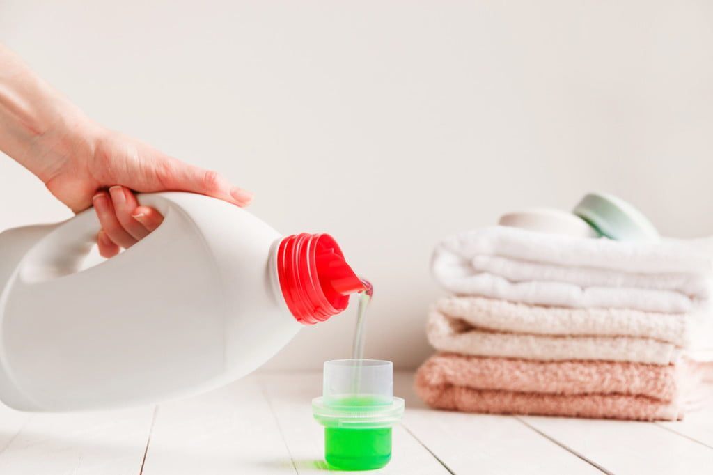 Lhand pouring liquid laundry detergent