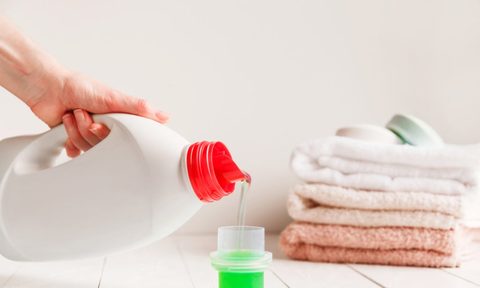 Lhand pouring liquid laundry detergent