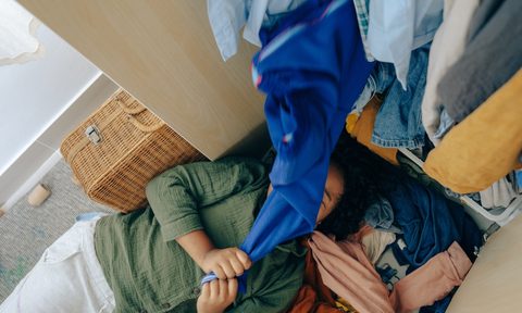 Young woman pulling clothes in a closet