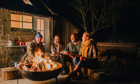Two couples using a backyard firepit at night