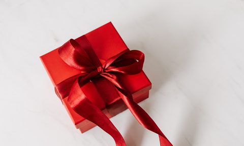 Holiday gift with a red bow on white surface