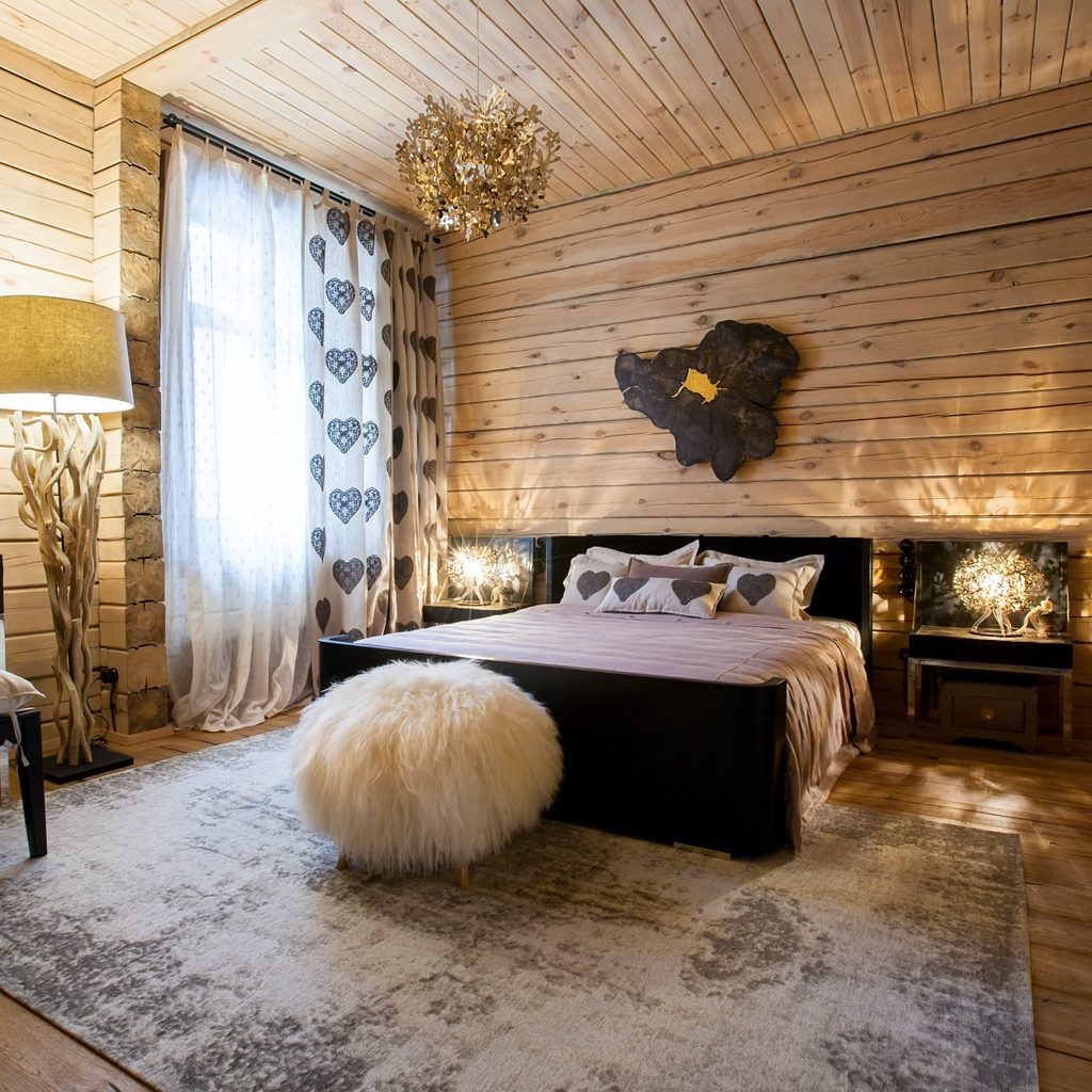 A rustic bedroom with wooden walls and floor rug