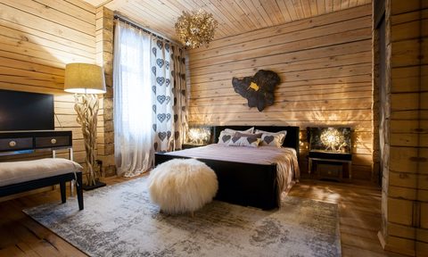 A rustic bedroom with wooden walls and floor rug