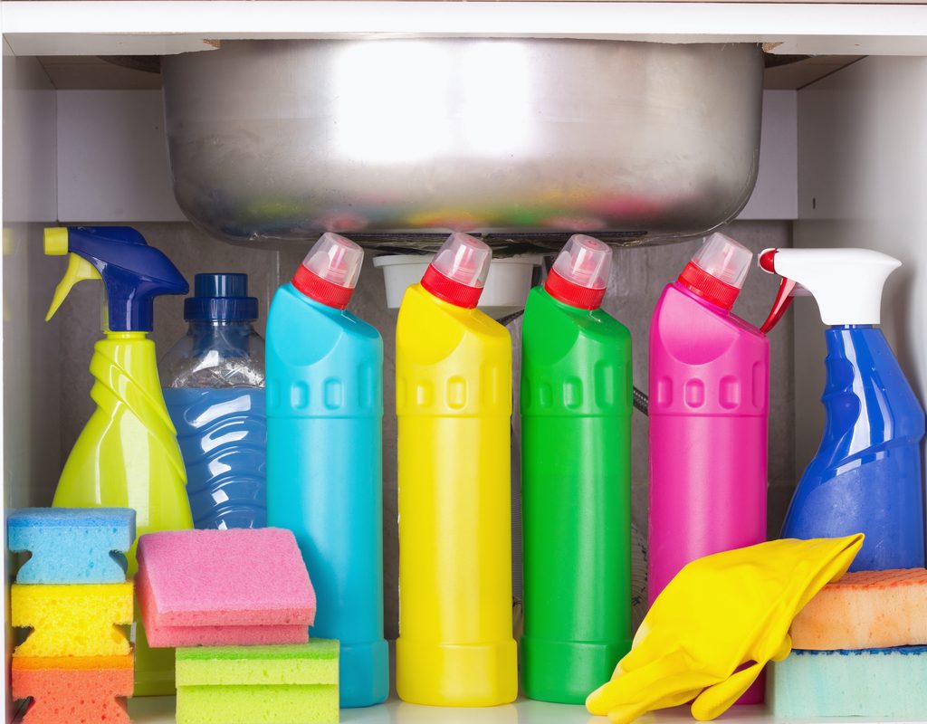 Several bottles of cleaning products under a sink