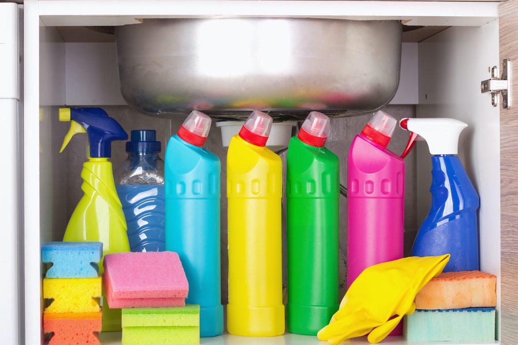 Several bottles of cleaning products under a sink