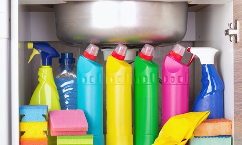 Several bottles of cleaning products under a sink