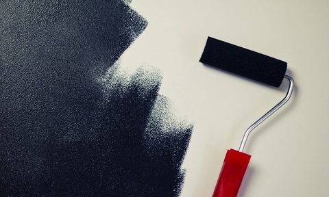 Red roller brush black paint on white wall