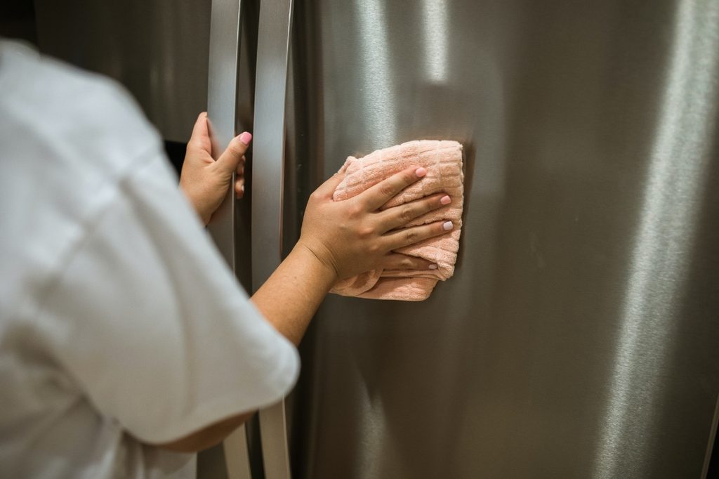 woman wiping refrigerator
