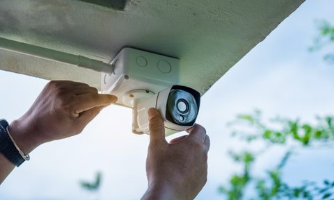 person installing wired home security camera