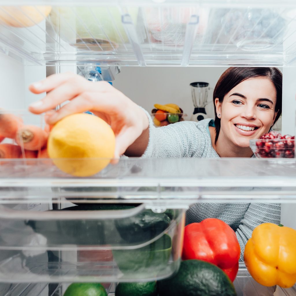 Woman opening fridge to get fruit