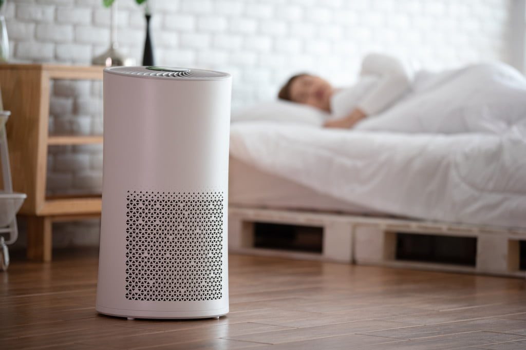 Person sleeping with an air purifier in a bedroom