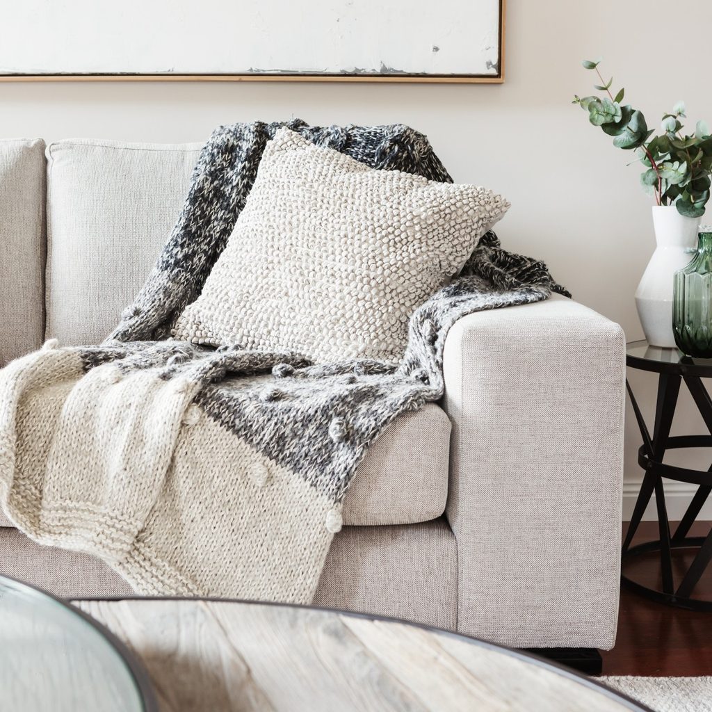 neutral couch with textured pillow and throw