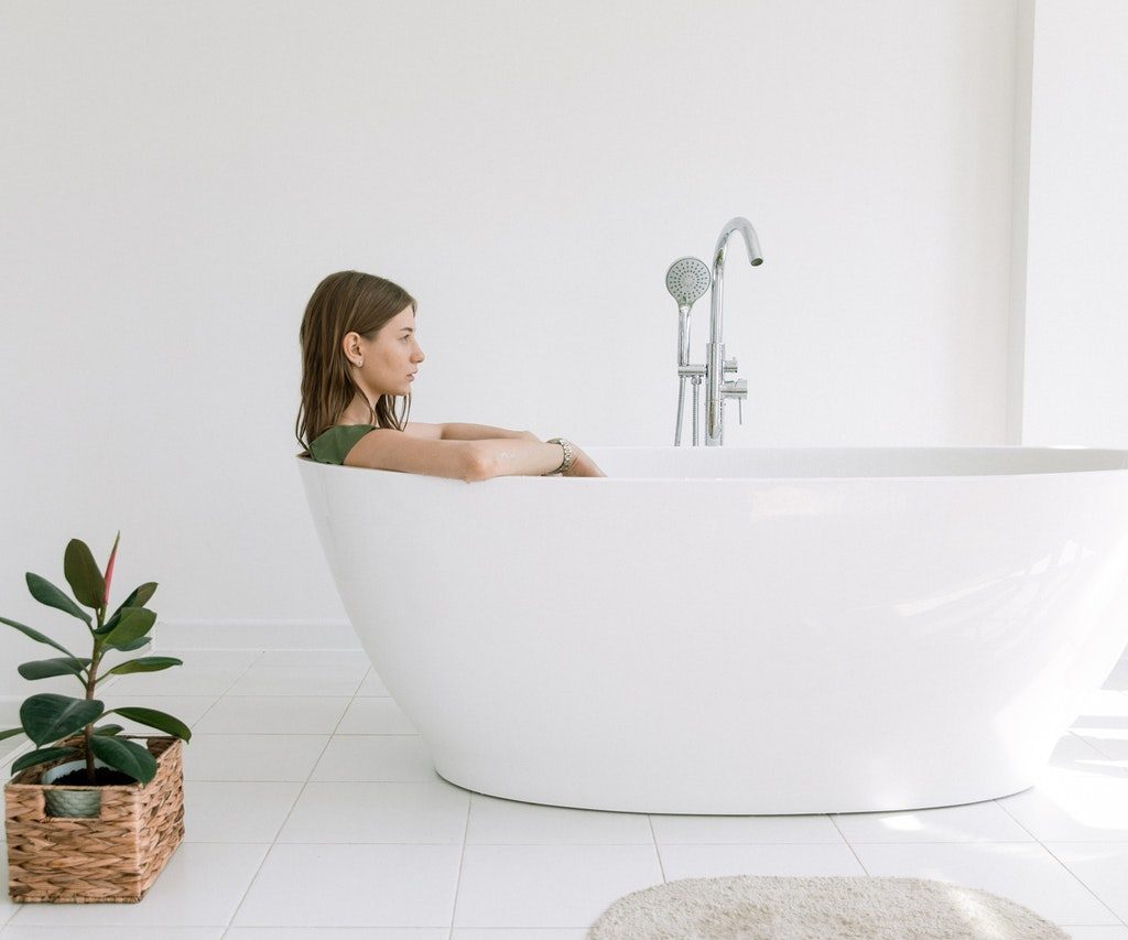 Woman in a tub next to a plant