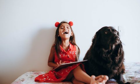 black lab and little girl on a bed