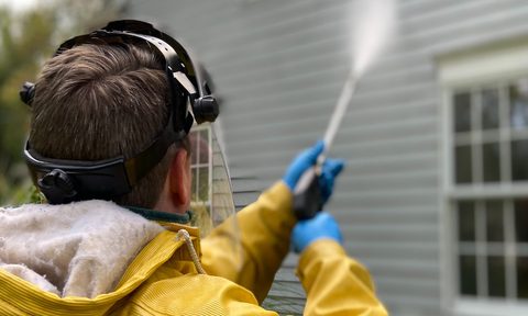 man pressure washing home