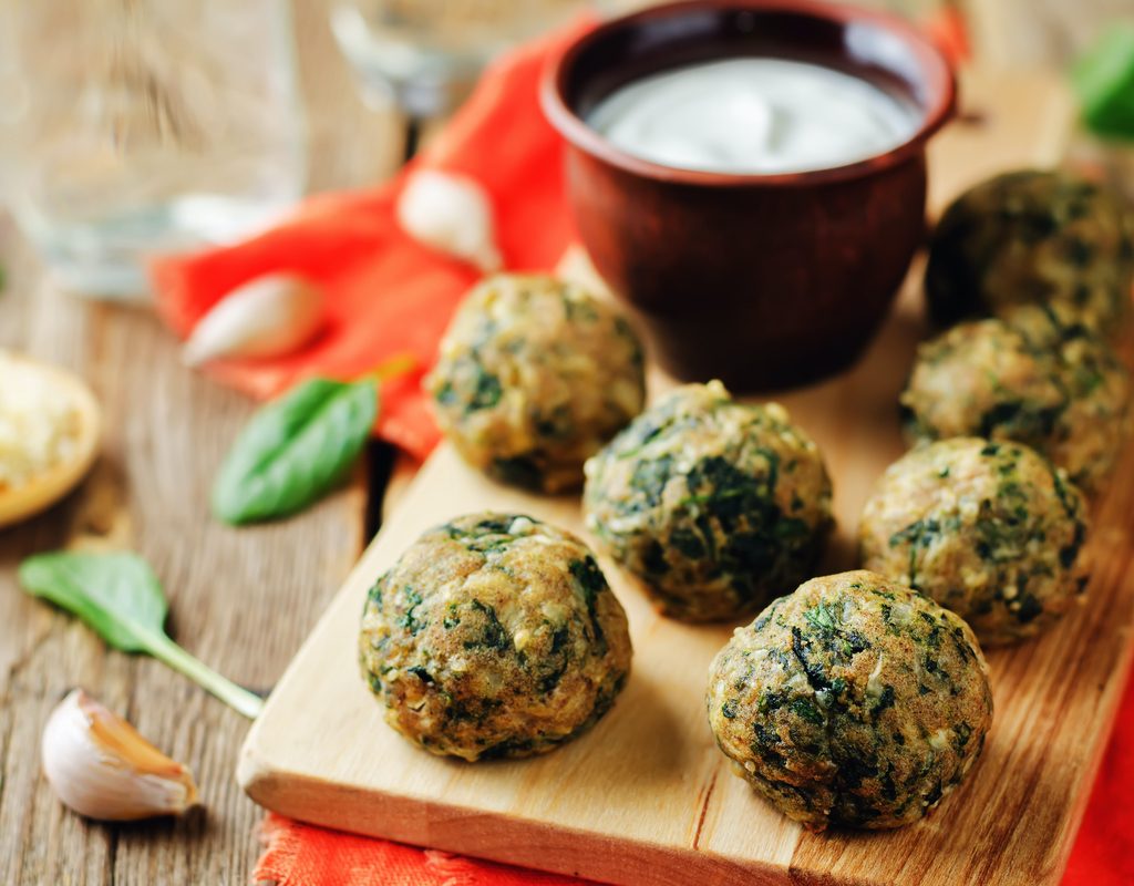 Spinach appetizer balls on a tray with dip