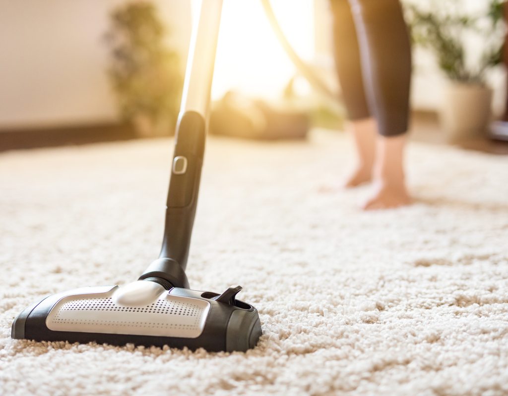 Woman vacuuming a white rug