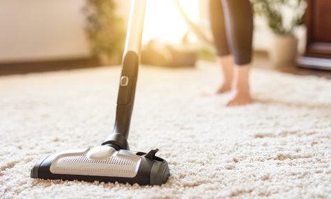 Woman vacuuming a white rug