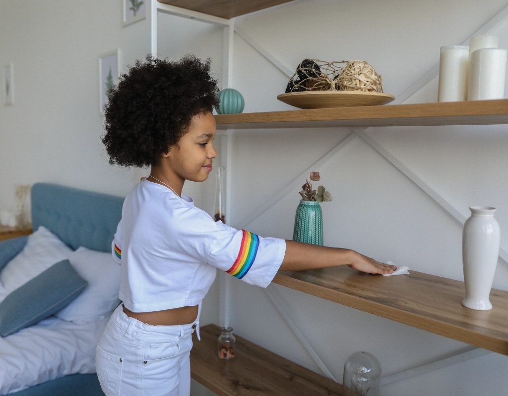 child wiping down a shelf with cloth
