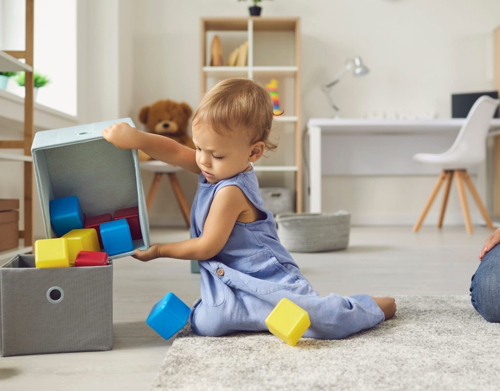 young child helping to clean up in playroom