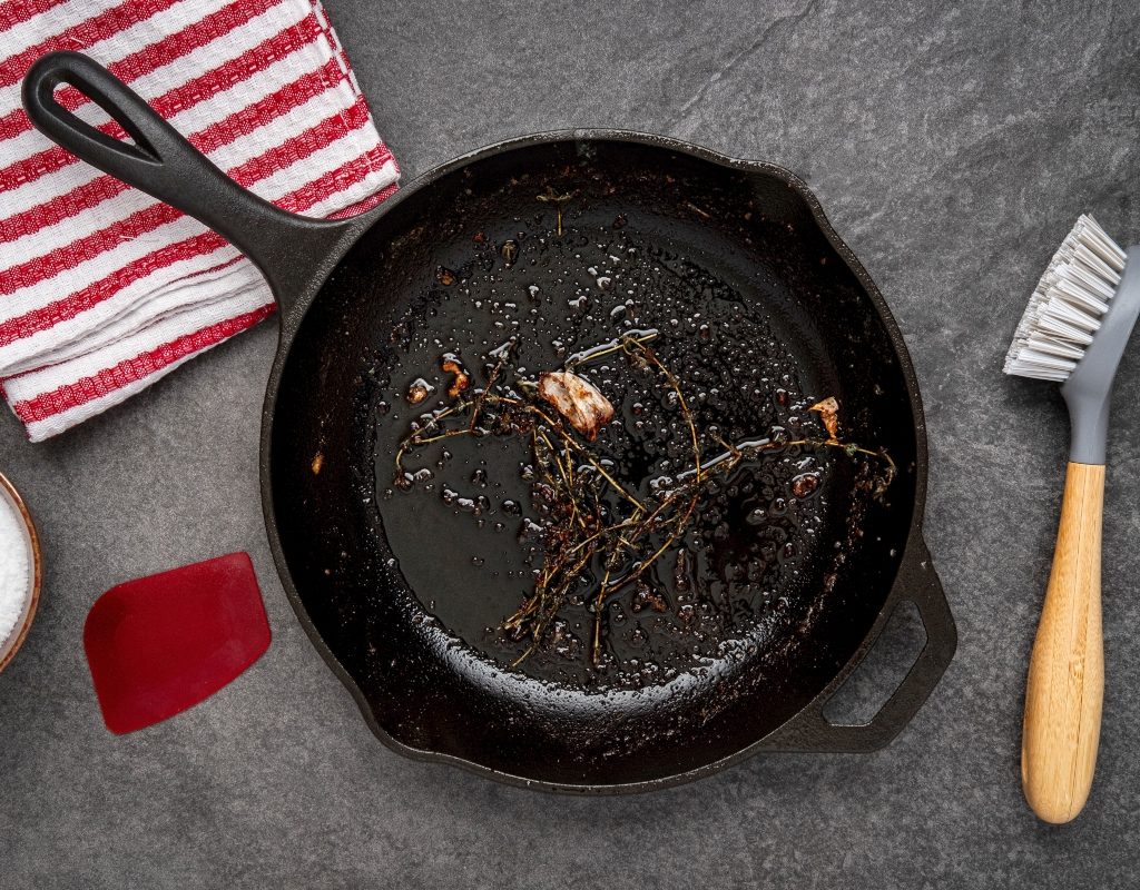 cleaning a dirty cast iron pan with brush