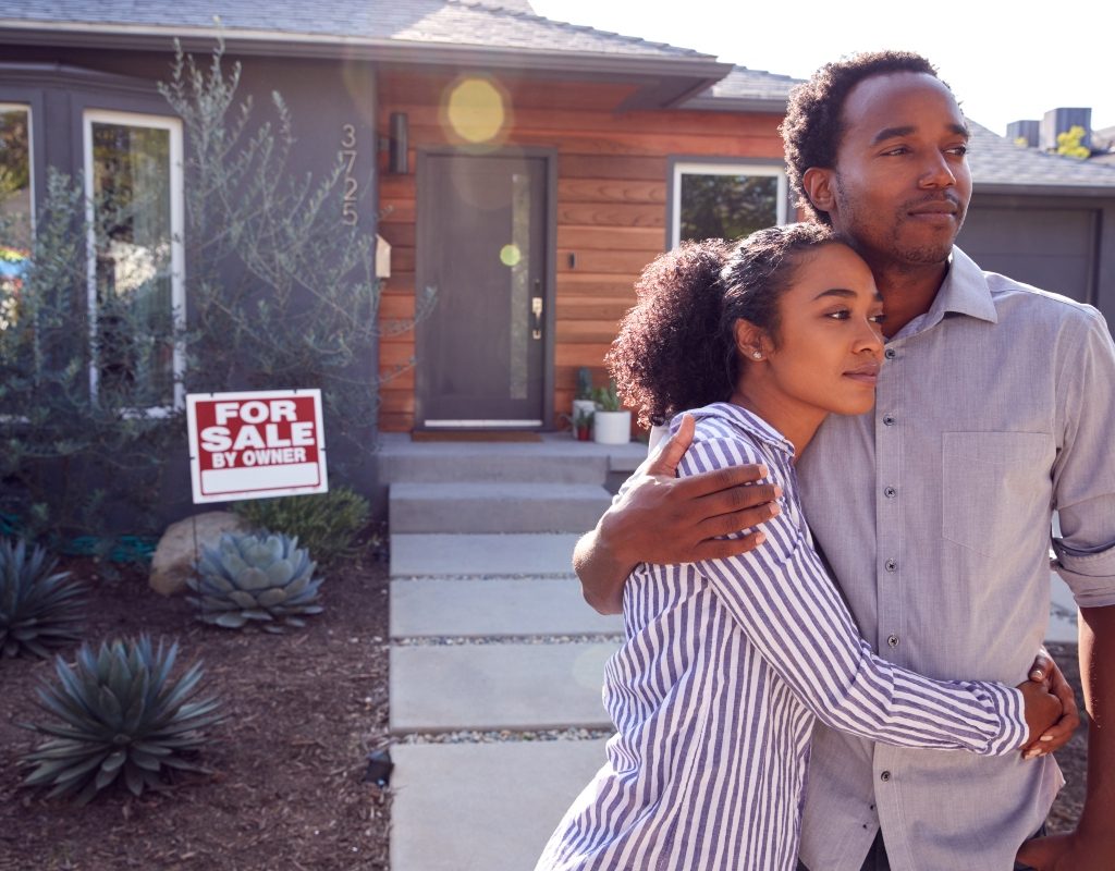 couple standing in front of home for sale