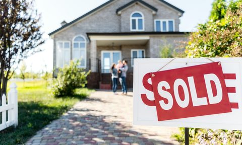 family in front of home with sold sign in yard