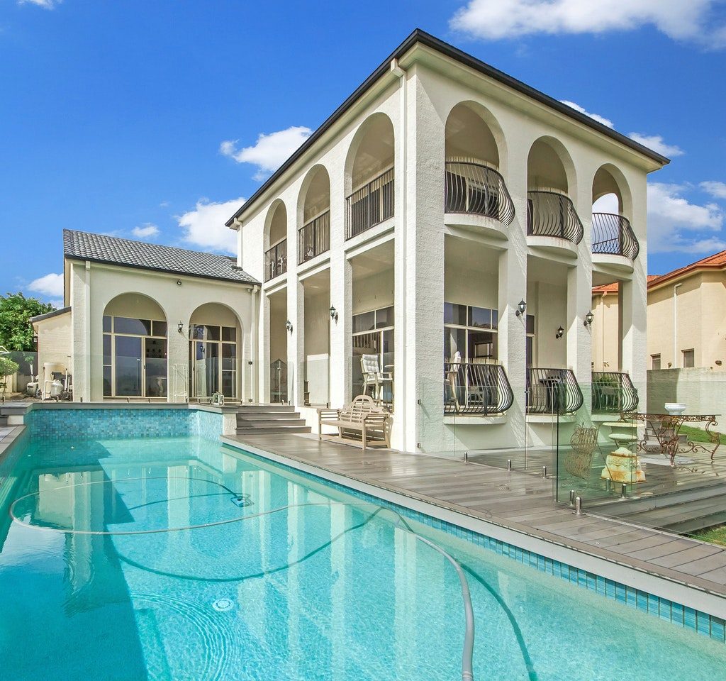 Outdoor inground pool with white two story home