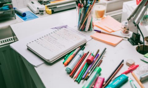 Desk with office supplies scattered about.