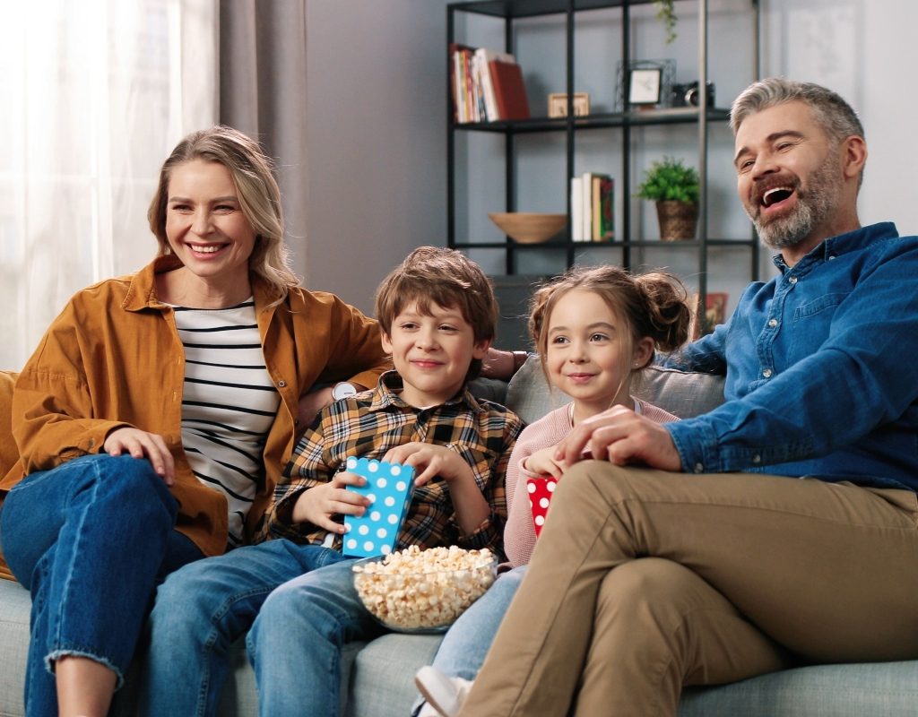 family sitting on couch watching tv together