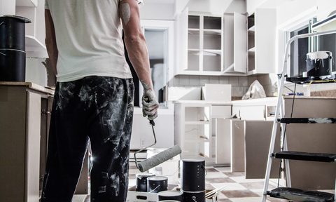 Man holding paint rolling after painting kitchen cabinets