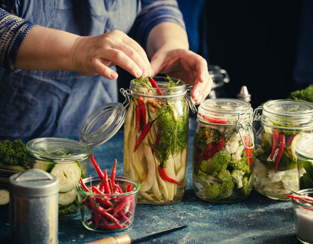 person canning chilis and vegetables