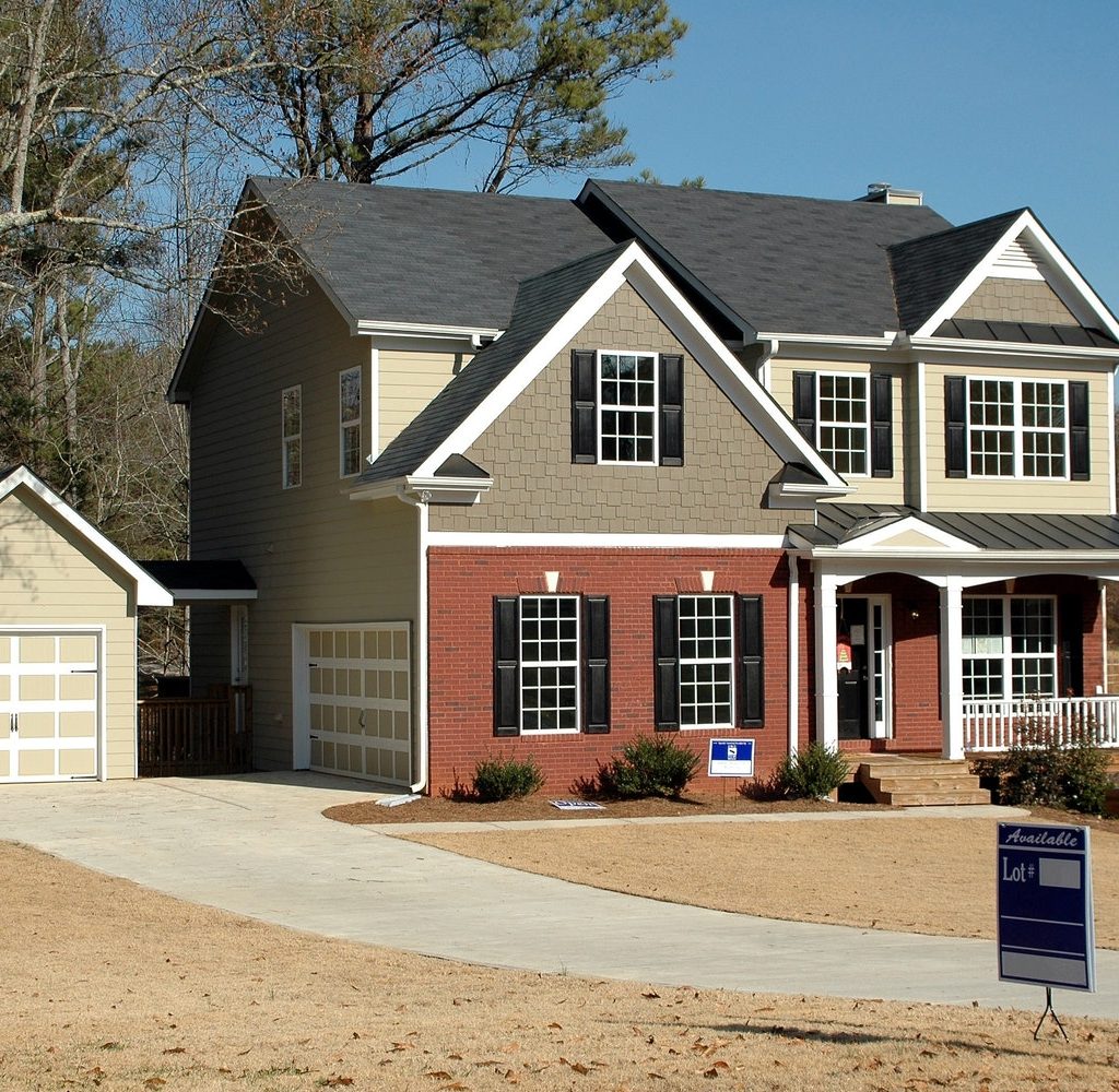 A house with a sale sign in the yard and a curved driveway