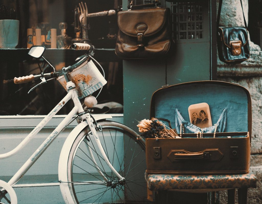 A vintage set up with an old bike and an old suitcase holding items.
