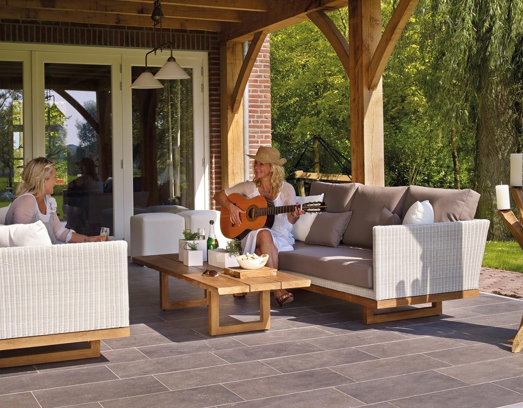 Two women on the patio with one playing the guitar