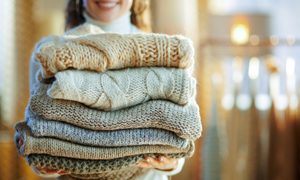 woman carrying folded winter sweaters