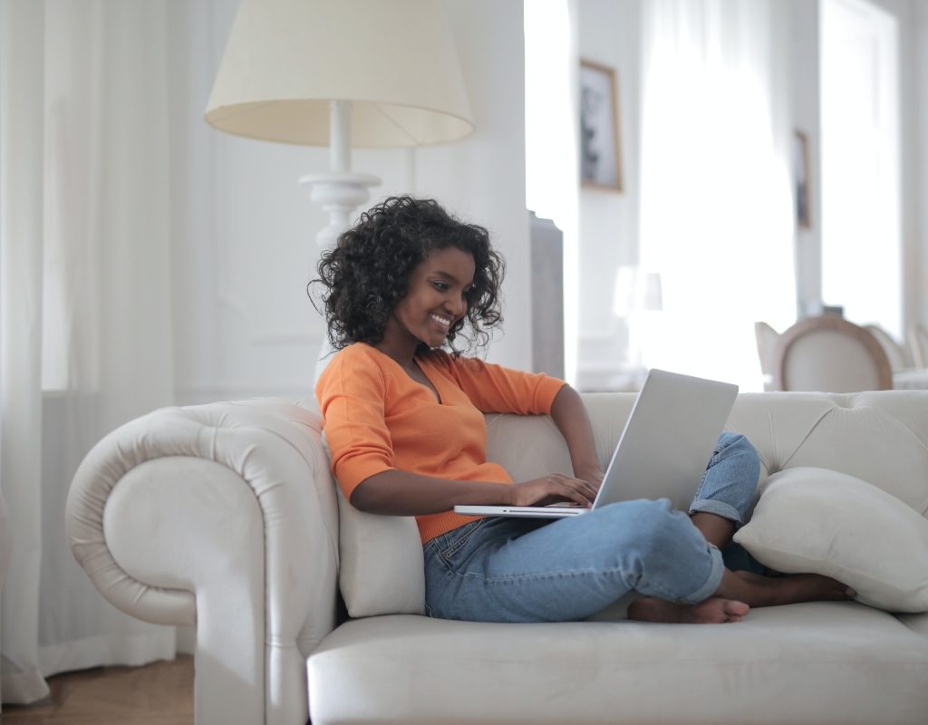 woman sitting on white couch with a laptop