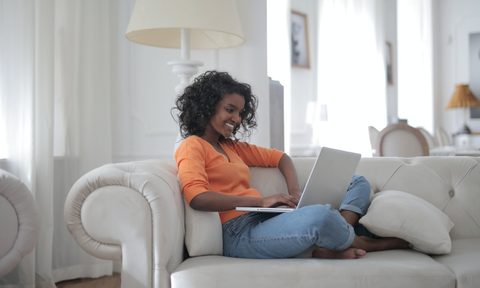 woman sitting on white couch with a laptop
