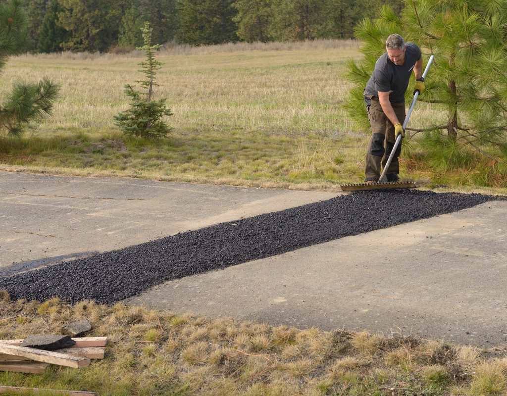 Person repairing an asphalt driveway