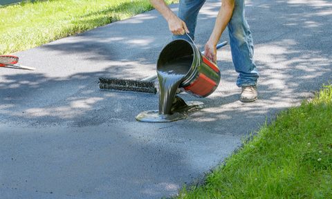 man applying asphalt sealant on a driveway
