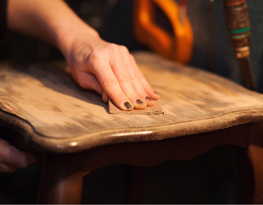 closeup of a hand sanding a chair seat