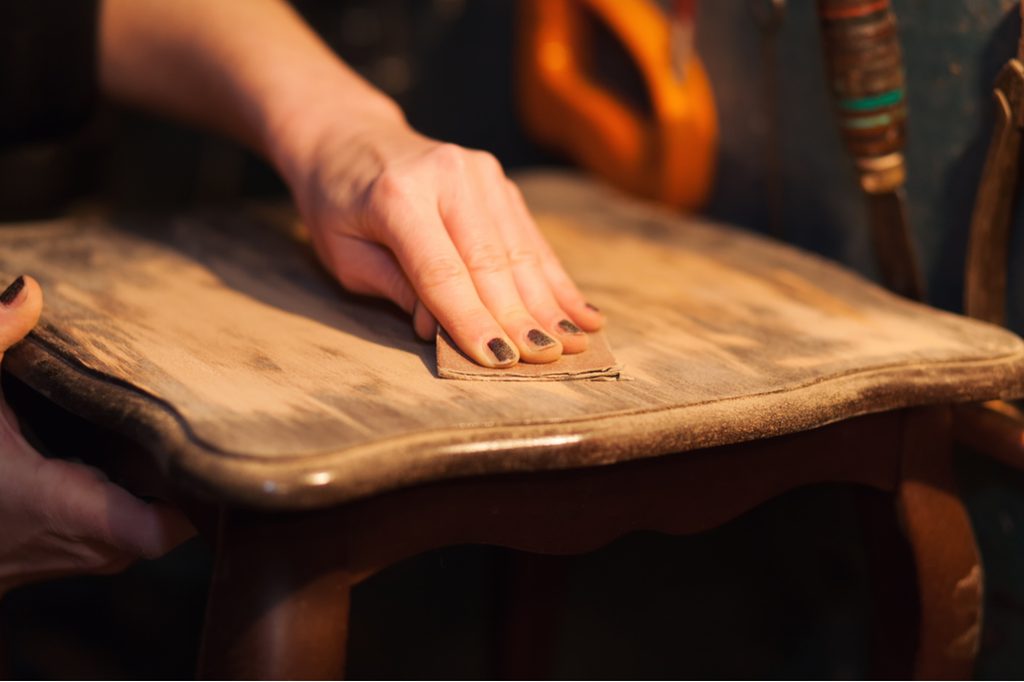 Close-up of a hand sanding a chair seat